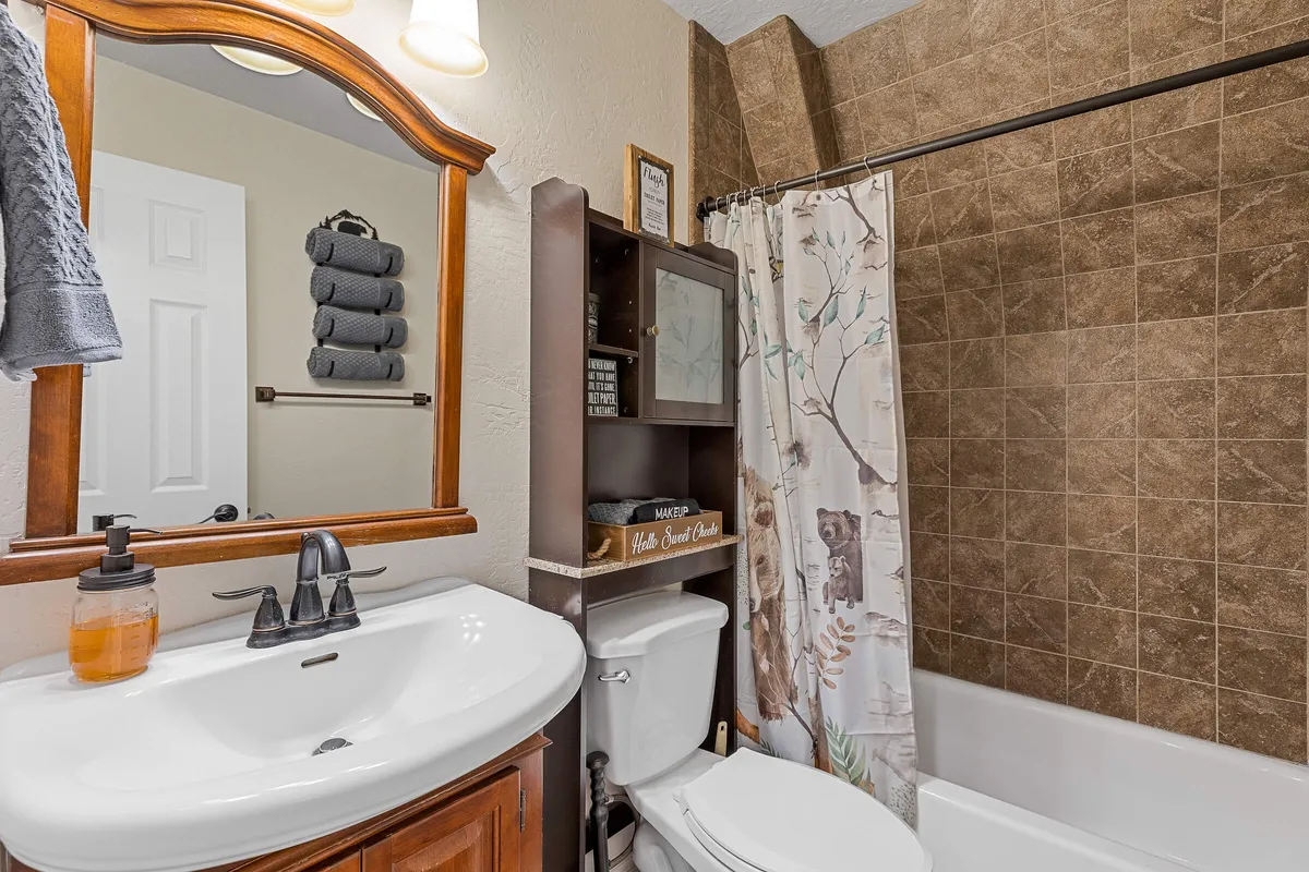 A serene bathroom setting with a mirror framed in wood, a modern sink and faucet, neatly stacked towels, and shelves decorated with calming accents. The soft lighting and natural materials create a soothing atmosphere perfect for self-care and relaxation.