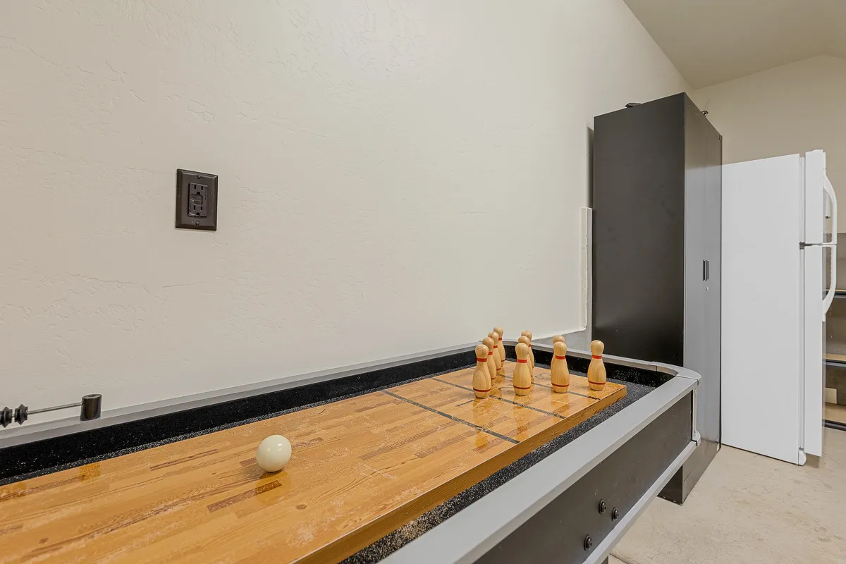 An interior shot of a shuffleboard table, wooden player pieces, and a social seating setup, creating a lively atmosphere for friendly competition and game nights. The casual setting invites both kids and adults to participate.