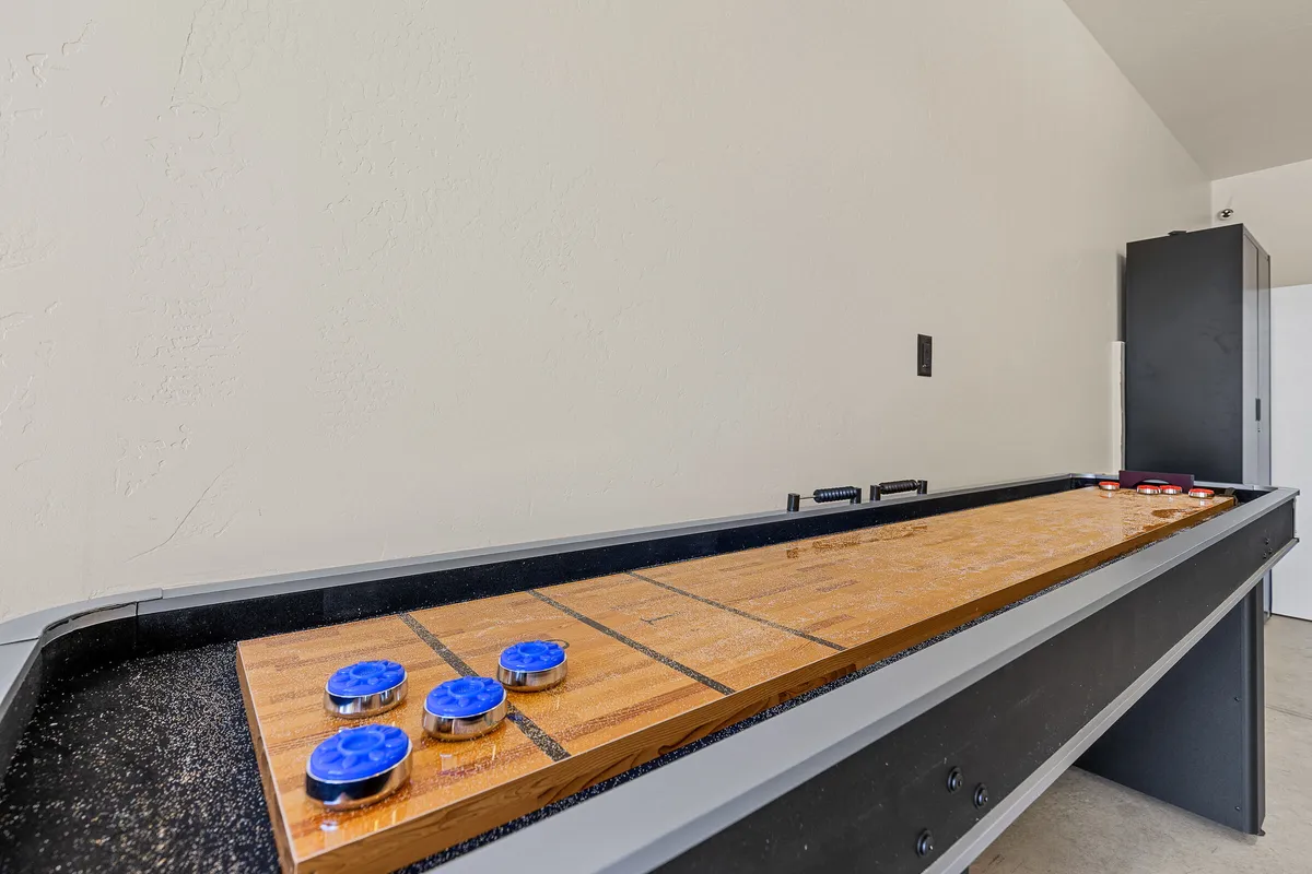 A shuffleboard table with blue pucks sits at the center of this lighthearted, inviting space, suggesting friendly matches and laughter-filled evenings among guests.