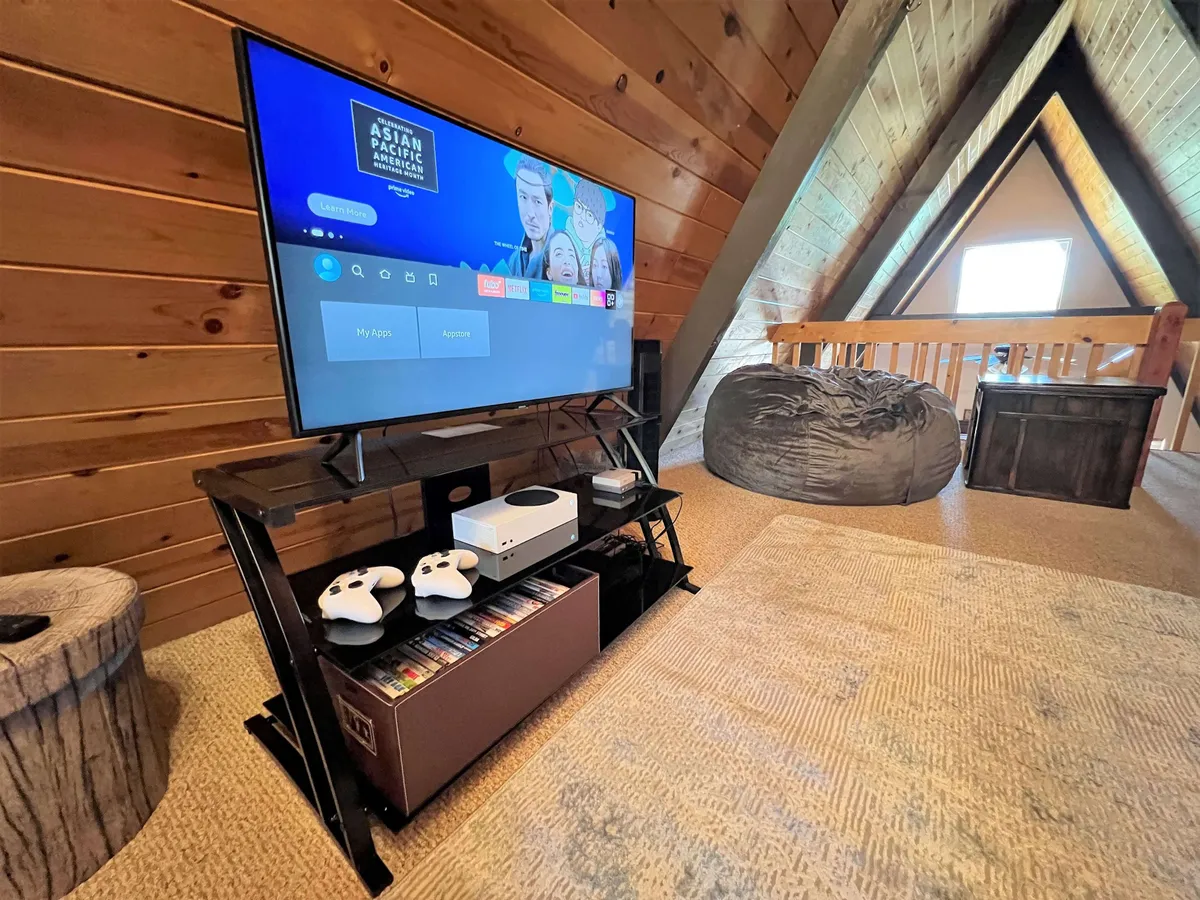 A relaxed, secondary lounge zone featuring a television, bean bag chair, wooden accents, and a gaming console. The setup is casual and comfortable, designed for movie marathons, game nights, or unwinding after a day of adventure.