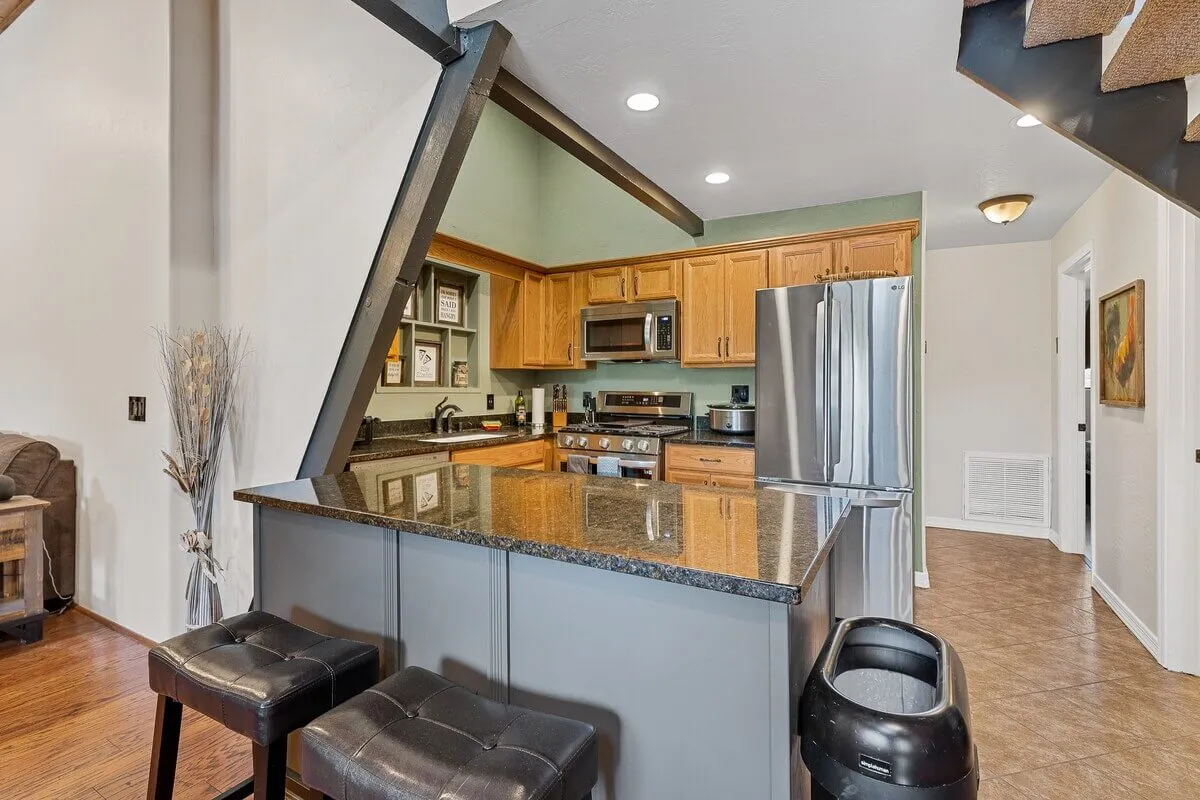 A welcoming kitchen scene featuring a spacious kitchen island, sleek stainless steel appliances, and warm wooden cabinetry. The layout is open and ideal for group cooking, with ample counter space and a modern yet rustic ambiance.