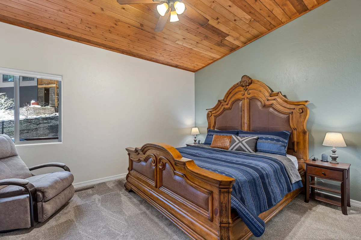 A bedroom scene featuring an ornate wooden bed, a comfortable armchair, and decorative lamps on either side. The space is filled with natural light, enhancing the sense of tranquility and inviting guests to rest or read in peace.
